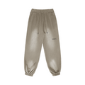 Beige minimalist sweatpants with BRKN. logo, drawstring waist, and tapered cuffs for streetwear style